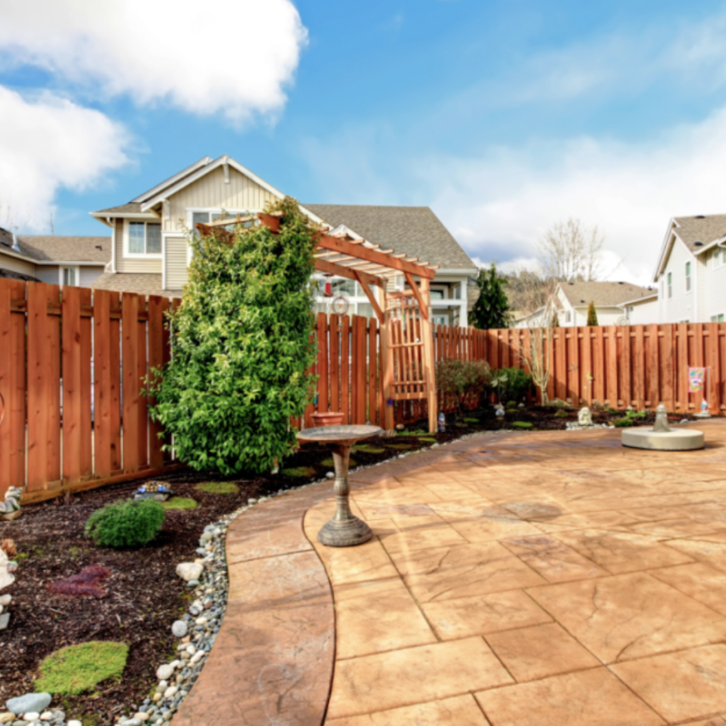 image of a newly hardscaped yard with stone edging, shrubbery and stone pavers.